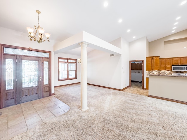entryway featuring vaulted ceiling, light carpet, an inviting chandelier, and decorative columns