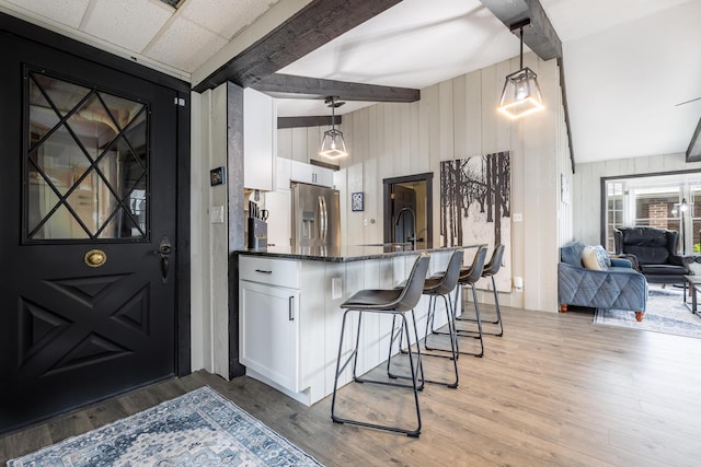 11181 Elm St, Lakeview, OH 43331 - kitchen with stainless steel fridge, a breakfast bar, white cabinetry, light wood-style flooring, and wooden walls
