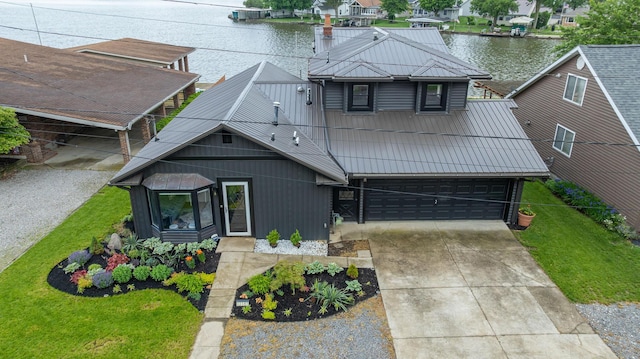 11181 Elm St, Lakeview, OH 43331 - view of front facade with a water view, concrete driveway, an attached garage, a front lawn, and metal roof