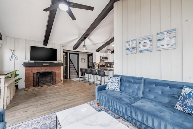 11181 Elm St, Lakeview, OH 43331 - living area with light wood finished floors, a ceiling fan, a fireplace, beamed ceiling, and wooden walls