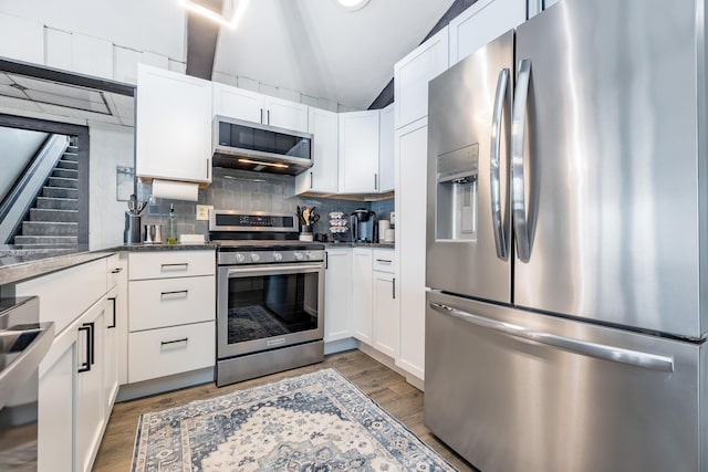 11181 Elm St, Lakeview, OH 43331 - kitchen featuring appliances with stainless steel finishes, light wood finished floors, vaulted ceiling, tasteful backsplash, and white cabinetry