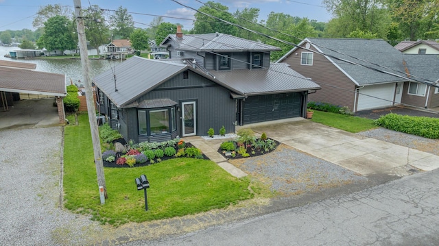 11181 Elm St, Lakeview, OH 43331 - view of front of property with metal roof, a front yard, concrete driveway, an attached garage, and a water view