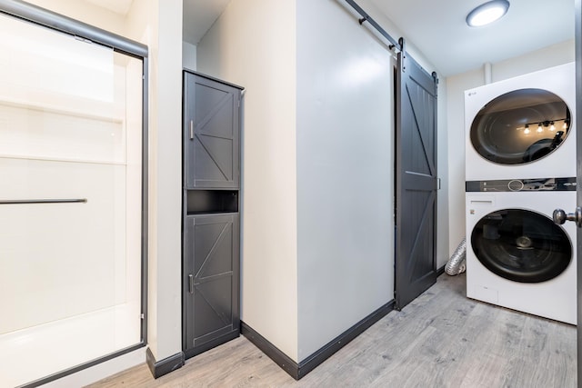 11181 Elm St, Lakeview, OH 43331 - laundry area with stacked washing machine and dryer, light wood finished floors, a barn door, and baseboards