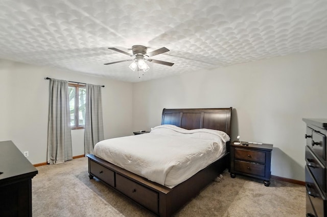 bedroom featuring light colored carpet, baseboards, and ceiling fan