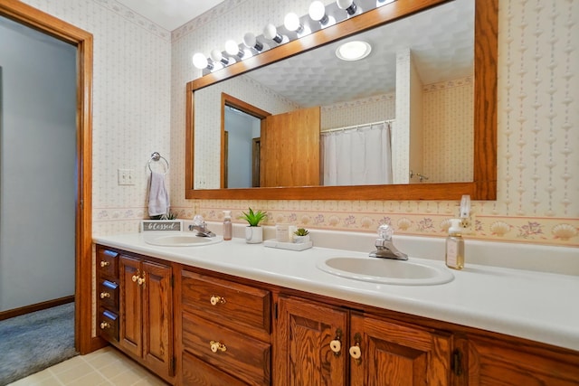 bathroom featuring double vanity, wallpapered walls, and a sink