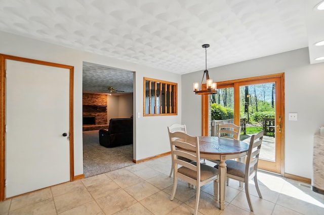 dining space with baseboards, a chandelier, light tile patterned floors, and a fireplace