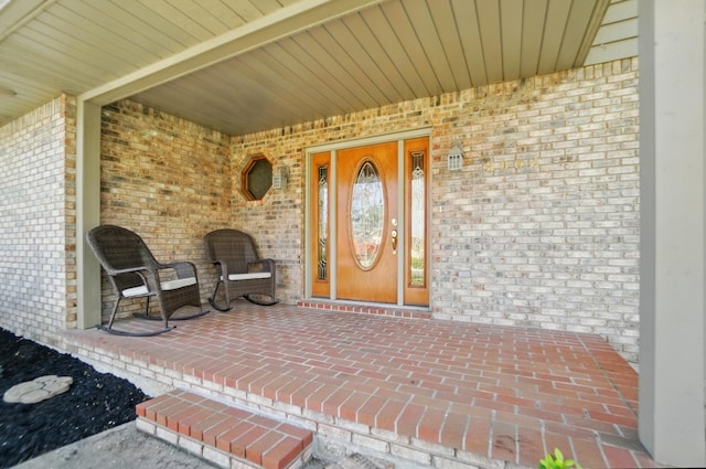 property entrance featuring a porch and brick siding