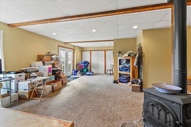 interior space with french doors, a paneled ceiling, carpet floors, and a wood stove