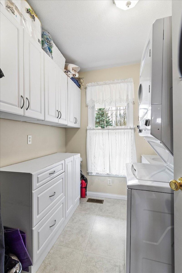 laundry room featuring cabinets, light tile patterned floors, and a textured ceiling