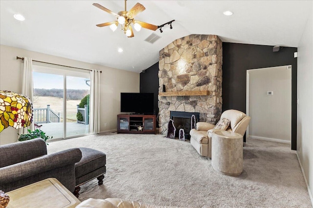 carpeted living room with a stone fireplace, lofted ceiling, and ceiling fan