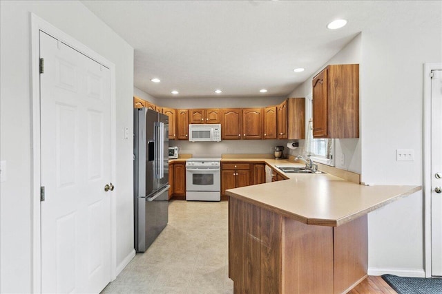 kitchen with sink, white appliances, and kitchen peninsula