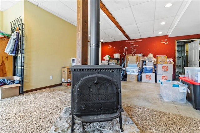 room details featuring a wood stove, a paneled ceiling, and concrete floors