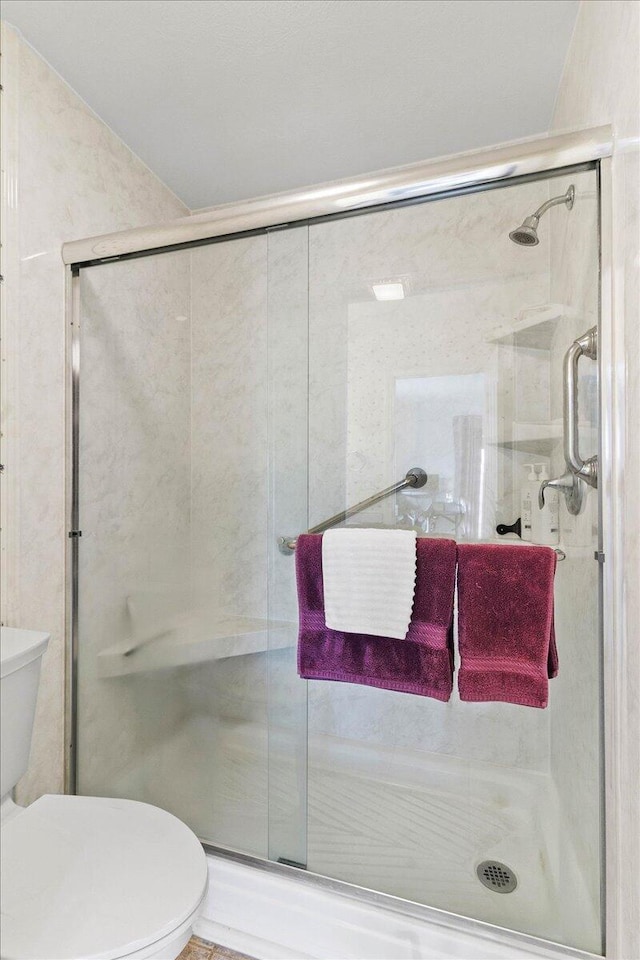 bathroom featuring toilet and an enclosed shower