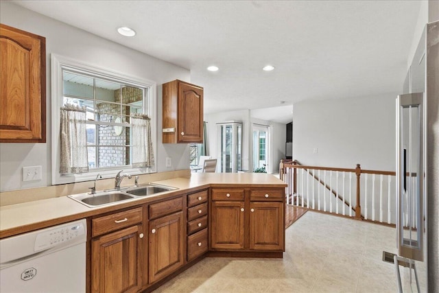 kitchen with white dishwasher, kitchen peninsula, and sink