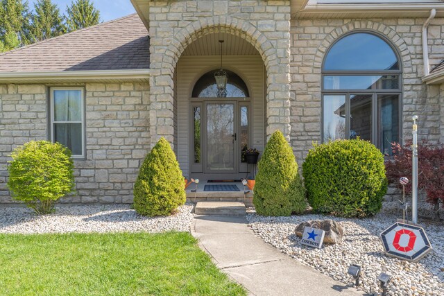 property entrance with roof with shingles and stone siding