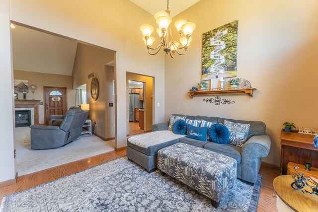 living area featuring baseboards, wood finished floors, a fireplace, and a notable chandelier