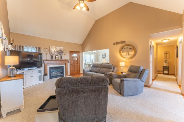 living area featuring ceiling fan, visible vents, high vaulted ceiling, and light colored carpet