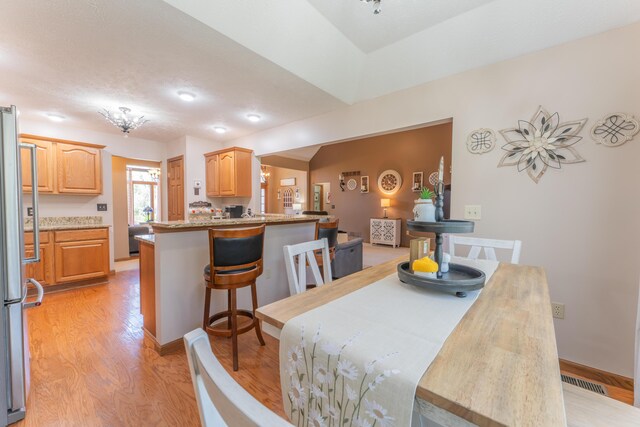 dining area with light wood-type flooring, visible vents, and baseboards