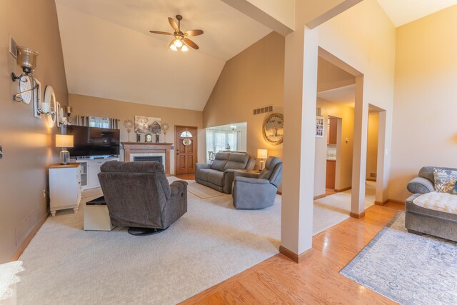 living room featuring visible vents, a ceiling fan, wood finished floors, a fireplace, and high vaulted ceiling