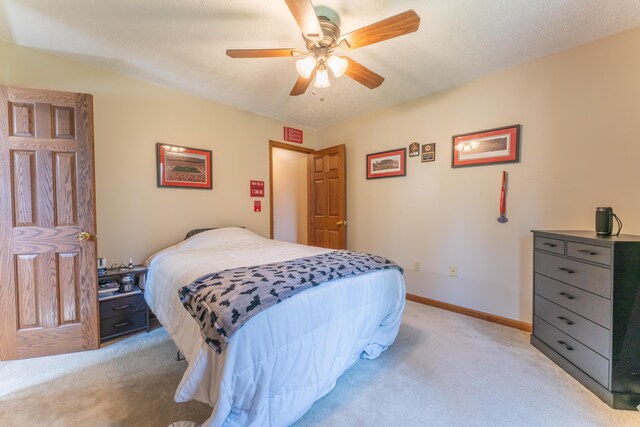 bedroom featuring light carpet, a ceiling fan, and baseboards
