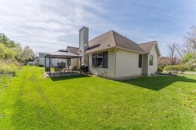 back of property featuring a chimney, a gazebo, a yard, and roof with shingles