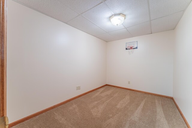 empty room with light carpet, a paneled ceiling, and baseboards