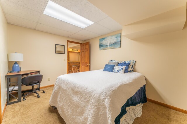 bedroom with baseboards, carpet flooring, and a drop ceiling