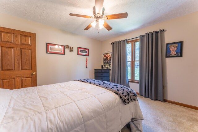 bedroom featuring baseboards, a textured ceiling, light colored carpet, and ceiling fan