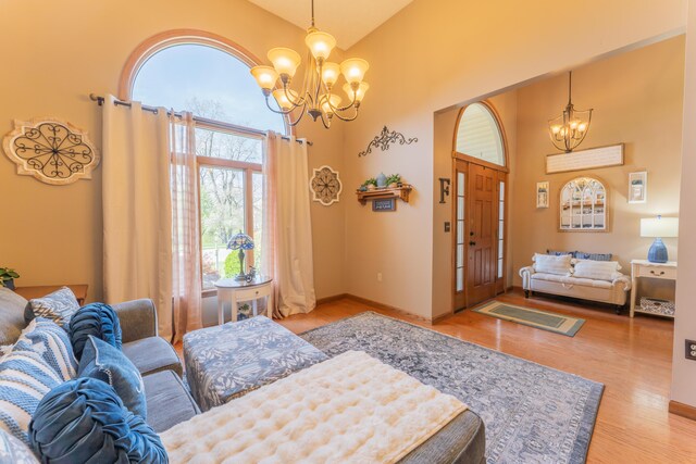 bedroom with a towering ceiling, a notable chandelier, wood finished floors, and baseboards