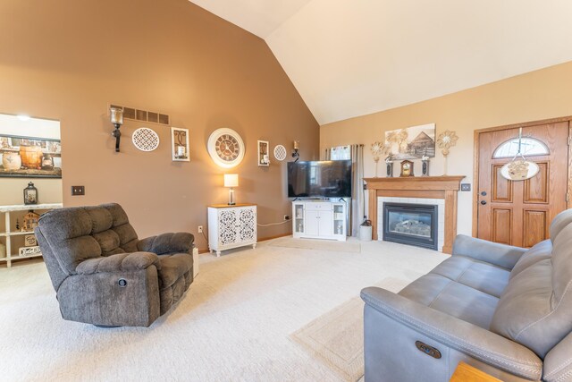 carpeted living area featuring baseboards, a tiled fireplace, visible vents, and high vaulted ceiling