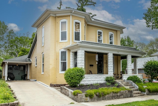 italianate house featuring covered porch, concrete driveway, brick siding, and an attached garage