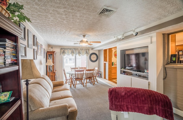 carpeted living room with ceiling fan, track lighting, visible vents, and a textured ceiling