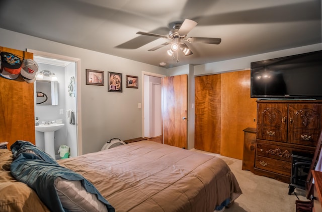 bedroom featuring a closet, ensuite bath, ceiling fan, carpet flooring, and a sink