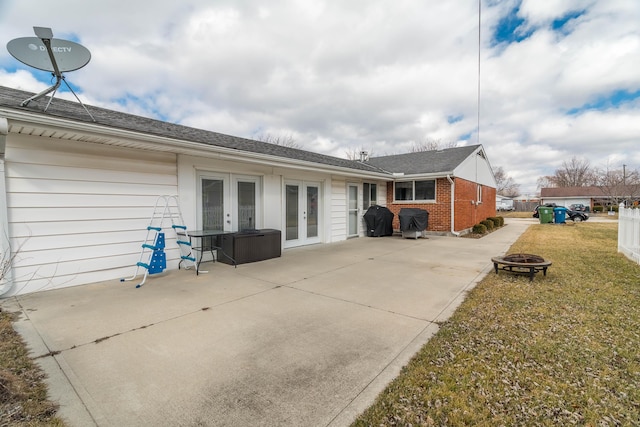 rear view of property featuring an outdoor fire pit, french doors, brick siding, and a patio area