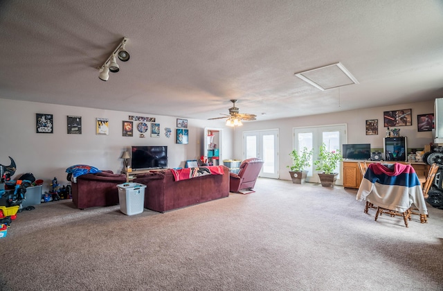 living area featuring attic access, french doors, light carpet, and a textured ceiling