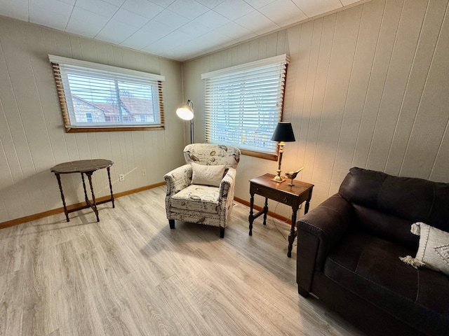 living area with light hardwood / wood-style flooring and wood walls