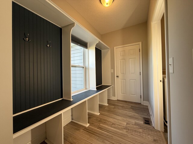 mudroom with baseboards, wood finished floors, and a textured ceiling