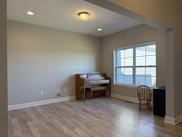 living area featuring baseboards, wood finished floors, recessed lighting, and a textured ceiling