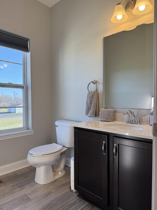 bathroom featuring toilet, vanity, baseboards, and wood finished floors