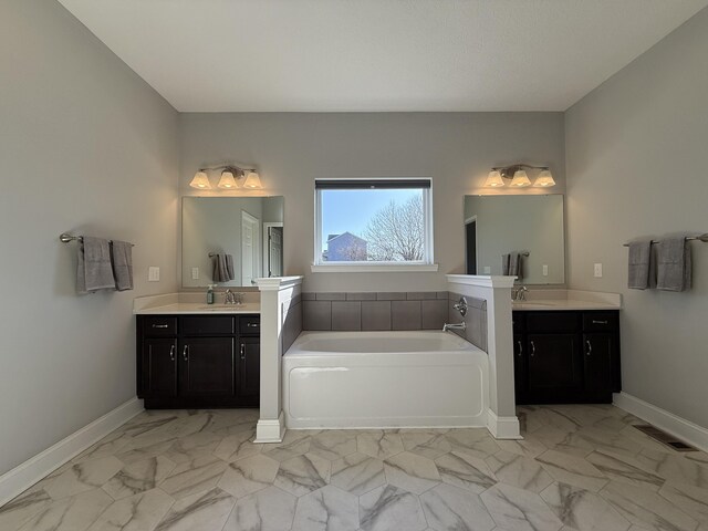bathroom featuring marble finish floor, baseboards, visible vents, and a bath