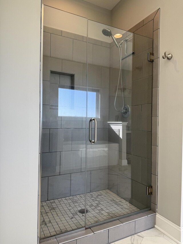 bathroom with baseboards, marble finish floor, and a stall shower