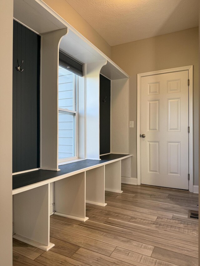 interior space featuring baseboards, visible vents, a textured ceiling, and wood finished floors