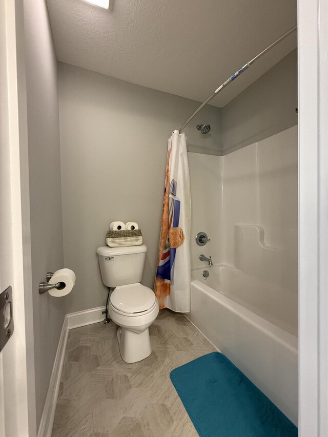 full bathroom with a textured ceiling, baseboards, toilet, and shower / bath combo with shower curtain