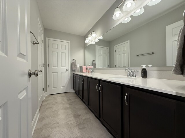 full bath with double vanity, baseboards, and a sink