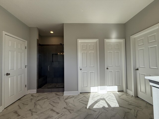 full bathroom with marble finish floor, baseboards, and a shower stall