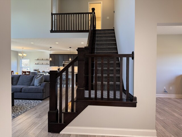 staircase with baseboards, a notable chandelier, wood finished floors, and recessed lighting
