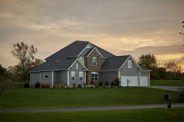 view of front of property with a lawn, stone siding, and concrete driveway