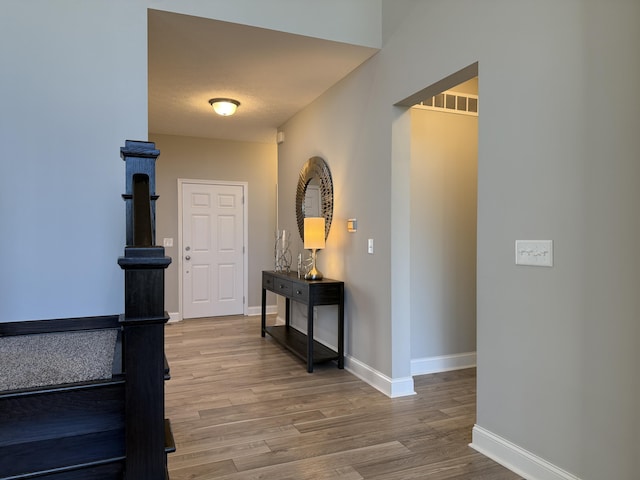 hall featuring visible vents, a textured ceiling, baseboards, and wood finished floors