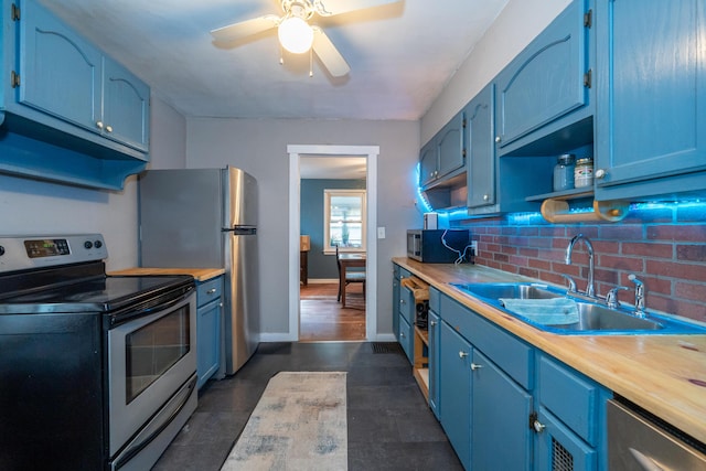 kitchen with appliances with stainless steel finishes, blue cabinets, sink, and wooden counters