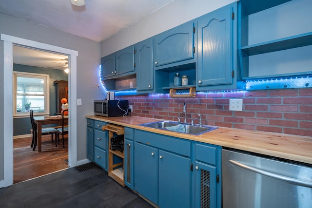 kitchen with appliances with stainless steel finishes, dark hardwood / wood-style floors, blue cabinets, sink, and wooden counters